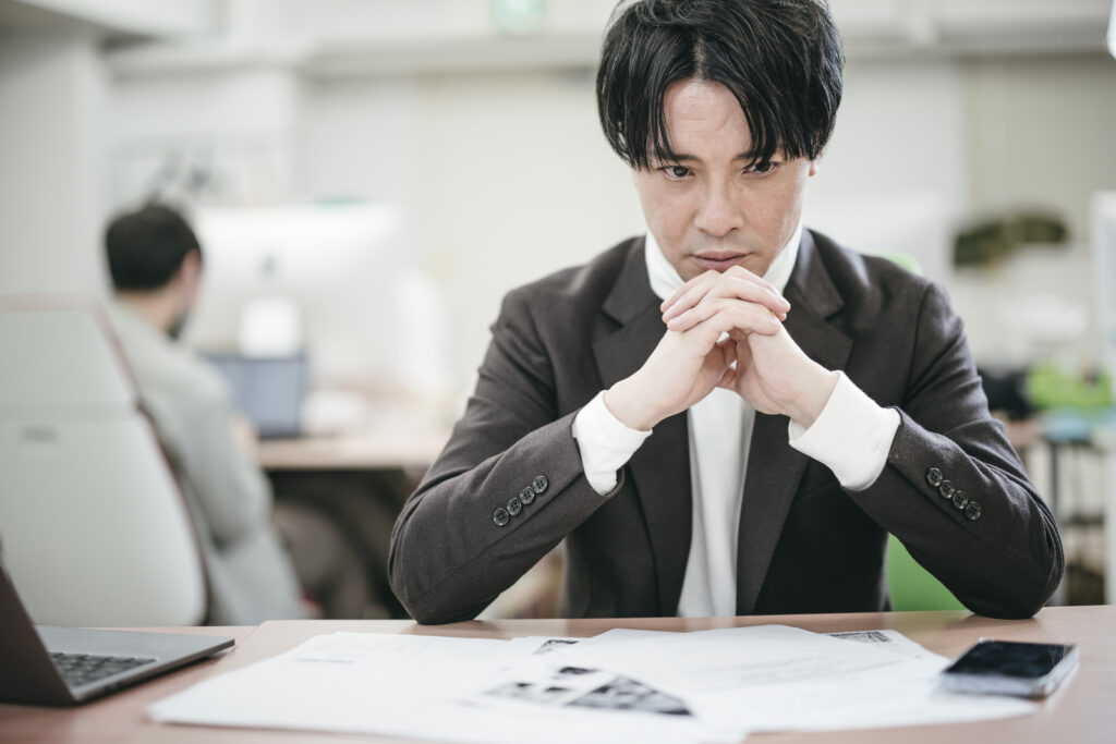デスクで悩んでいる男性の画僧